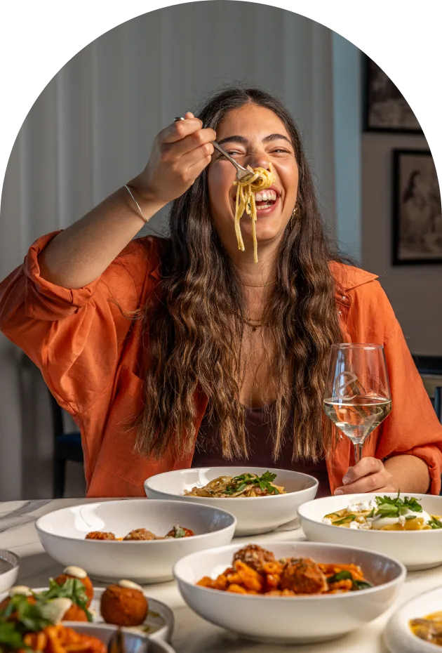 Guest enjoying a forkful of pasta at a shared table at Enzo's Cucina